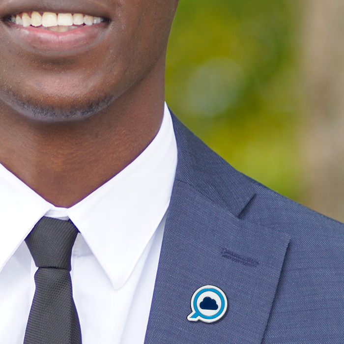 A man wearing a blue suit with a blue and white pin badge